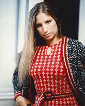 Barbra Streisand 1965 körül, egy bohém hangulatú, piros-fehér mintás ruhában, hosszú, egyenes hajjal – megjelenése tökéletesen tükrözi a korszak szabadszellemű stílusát.