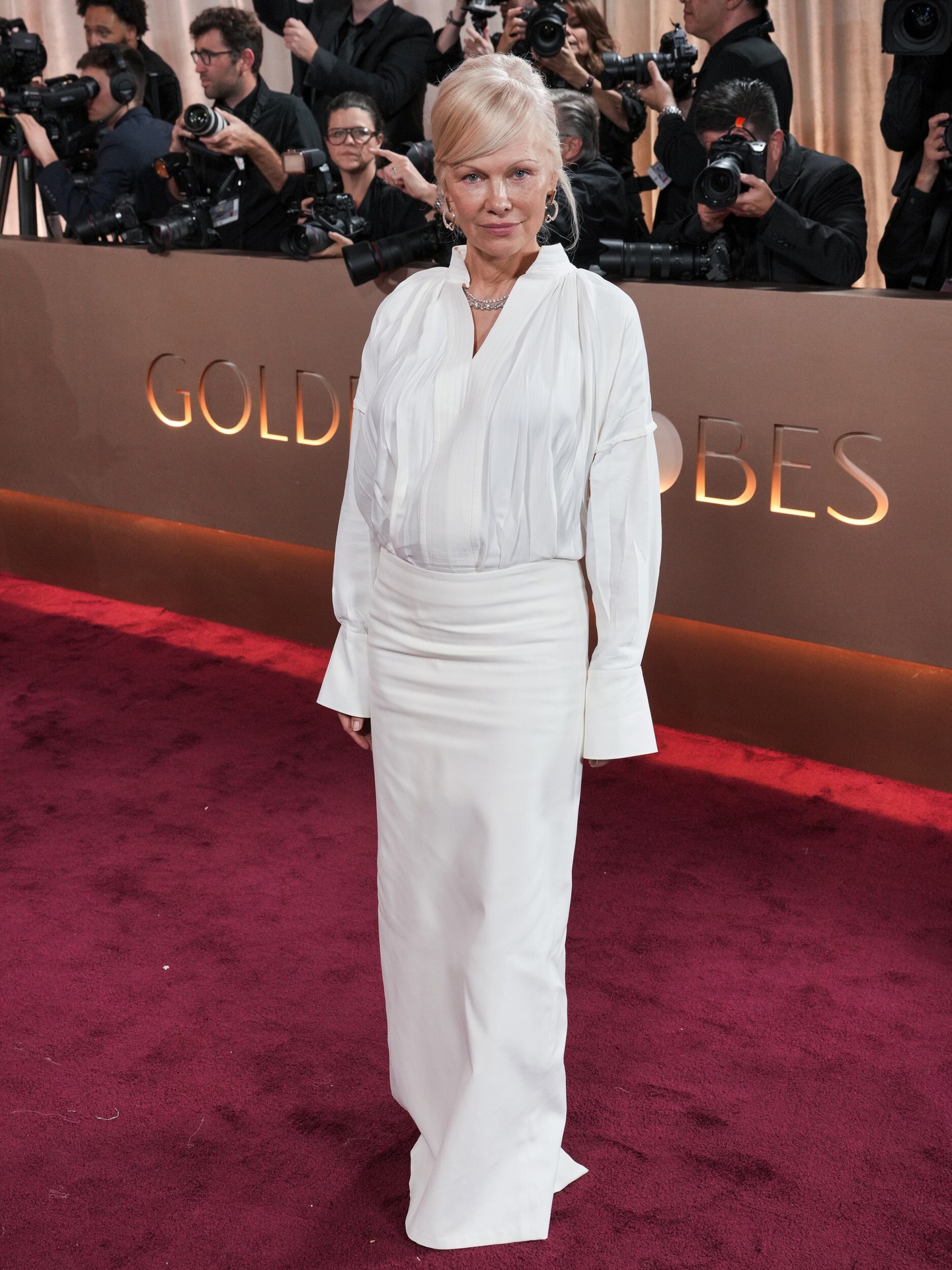 Az 58 éves Pamela Anderson hófehér Ferragamo szettben jelent meg a Golden Globe-díjátadón, ami tökéletesen bizonyítja, hogy egy elegáns fehér ing nemcsak a hétköznapokban, de a vörös szőnyegen is megállja a helyét. Az összeállítást ezüst karika fülbevalókkal és csillogó gyémánt nyaklánccal koronázta meg. 