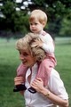 Diana hercegné, amint épp a vállán viszi Harry herceget a highgrove-i birtok zöld gyepén 1986 nyarán. A játékos közelség és Diana derűs arckifejezése arról árulkodik, mennyire élvezte az anyaság minden apró mozzanatát.