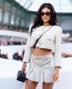 Kylie Jenner egy krémszínű, hasvillantós tweed blézert és hozzáillő miniszoknyát viselt, amit Chanel kiegészítőkkel koronázott meg.