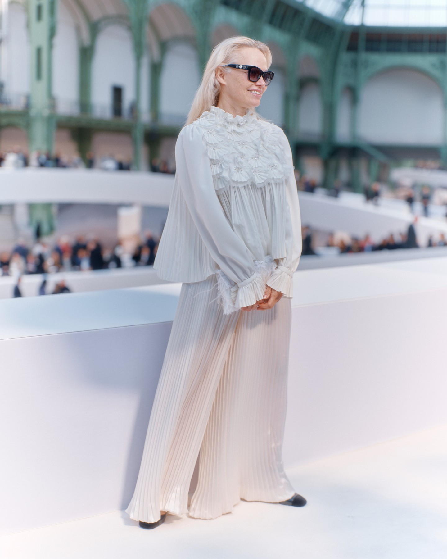 Pamela Anderson egy könnyed, fehér, kreppelt blúzban, és hozzáillő, szintén fehér, kreppelt nadrágban érkezett a bemutatóra.